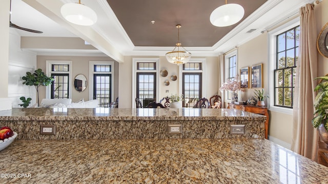 kitchen with hanging light fixtures, crown molding, and a healthy amount of sunlight