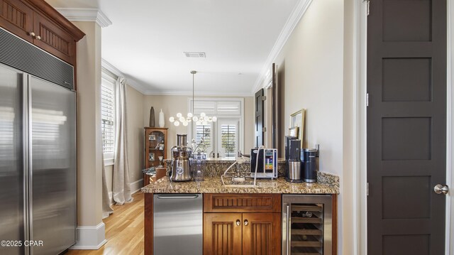 bar featuring stone countertops, decorative light fixtures, beverage cooler, built in refrigerator, and crown molding