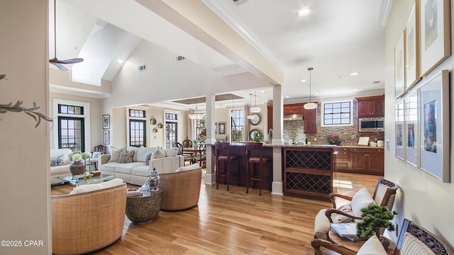 living room with ornamental molding, a high ceiling, light hardwood / wood-style flooring, and plenty of natural light