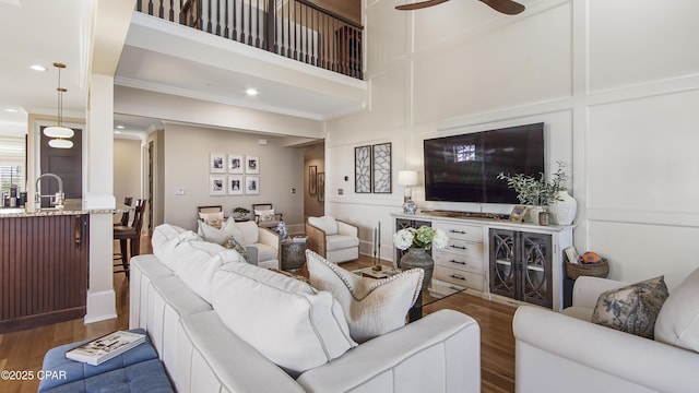 living room featuring hardwood / wood-style flooring, ceiling fan, crown molding, and sink