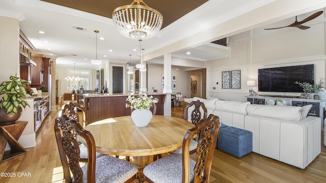 dining area featuring crown molding, ceiling fan with notable chandelier, and light wood-type flooring