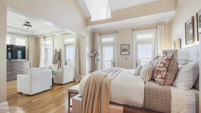 bedroom featuring multiple windows, crown molding, and light wood-type flooring