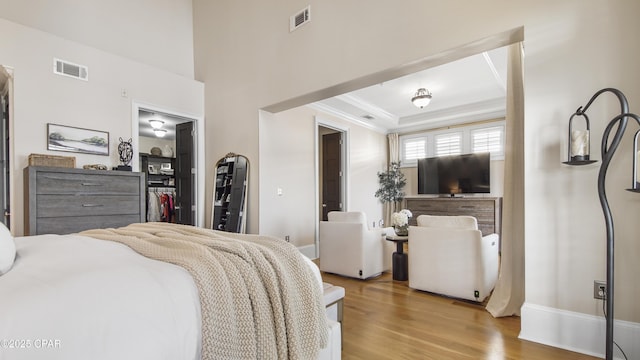 bedroom featuring crown molding, a raised ceiling, and light hardwood / wood-style floors