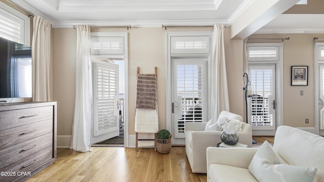 living area with ornamental molding, a healthy amount of sunlight, and light hardwood / wood-style flooring