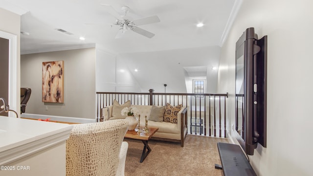 sitting room with ceiling fan, ornamental molding, and light carpet