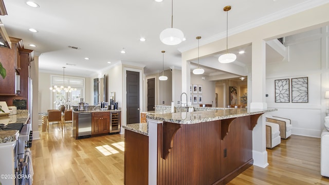 kitchen featuring wine cooler, stainless steel appliances, hanging light fixtures, and a large island with sink