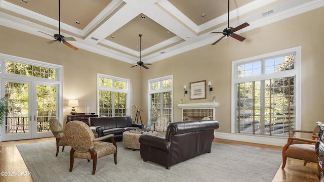 living room featuring crown molding, plenty of natural light, coffered ceiling, and light wood-type flooring