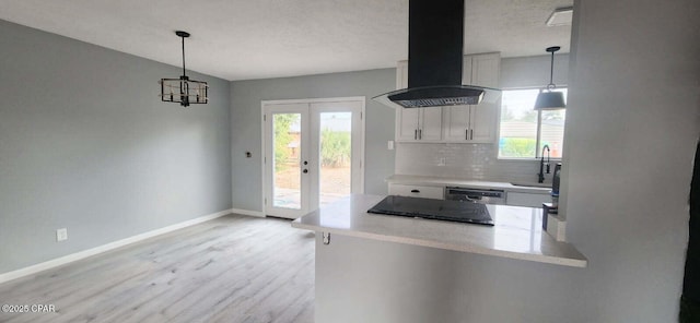 kitchen with tasteful backsplash, white cabinetry, sink, exhaust hood, and light hardwood / wood-style flooring