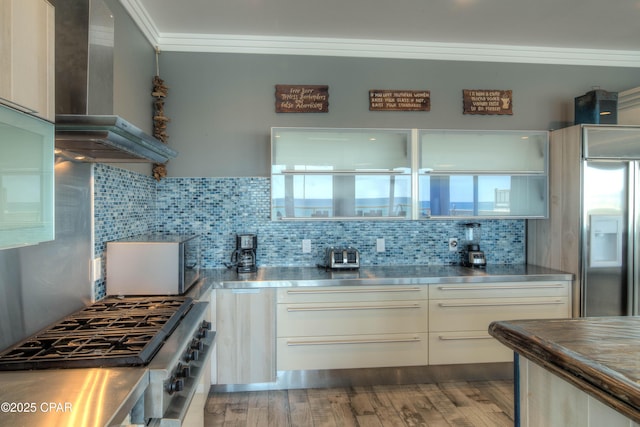 kitchen with stainless steel counters, tasteful backsplash, ornamental molding, cooktop, and wall chimney exhaust hood