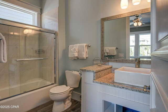 full bathroom with toilet, bath / shower combo with glass door, vanity, ceiling fan, and hardwood / wood-style floors