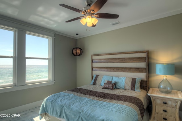 bedroom with crown molding, ceiling fan, and a water view