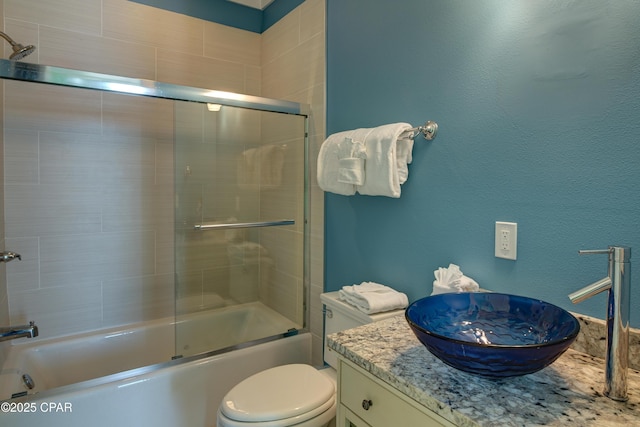 full bathroom featuring vanity, shower / bath combination with glass door, and toilet