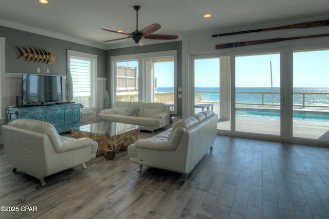 living room with wood-type flooring, a water view, ceiling fan, and crown molding