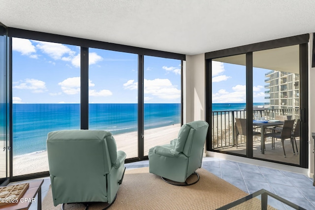 sunroom featuring a view of the beach and a water view