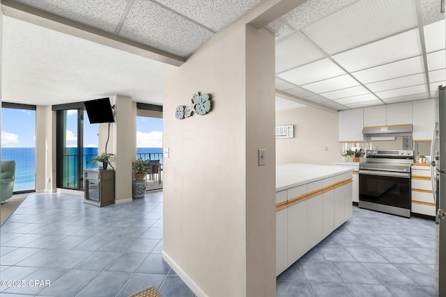 kitchen with a water view, white cabinets, a paneled ceiling, and electric range