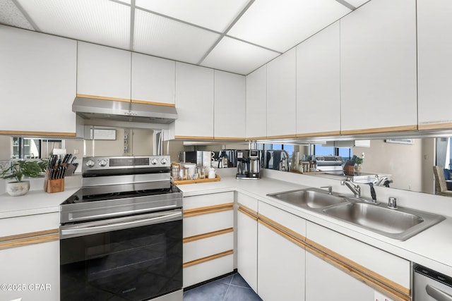 kitchen with sink, white cabinetry, light tile patterned floors, stainless steel appliances, and a drop ceiling