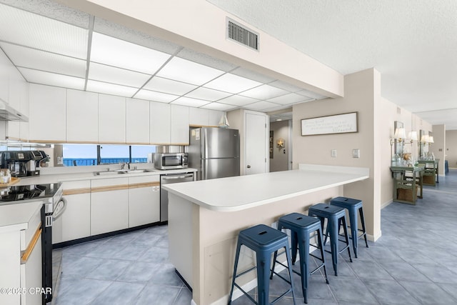 kitchen featuring stainless steel appliances, a breakfast bar area, white cabinets, and kitchen peninsula