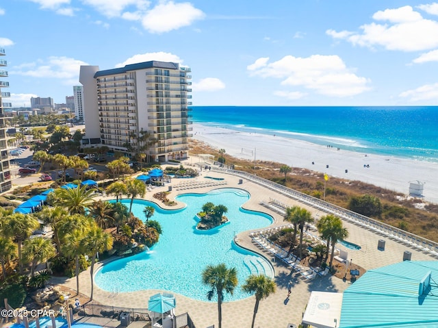 view of swimming pool with a water view, a beach view, and a patio