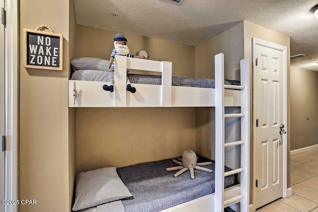 bedroom with a textured ceiling and light tile patterned floors