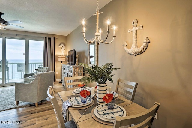 dining room featuring hardwood / wood-style flooring, ceiling fan with notable chandelier, and a textured ceiling
