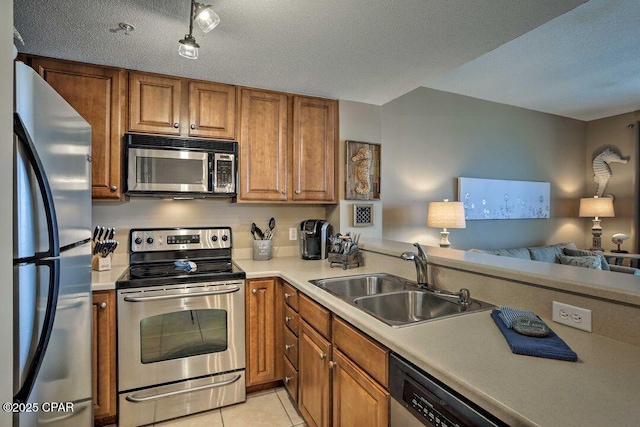 kitchen with light tile patterned flooring, appliances with stainless steel finishes, sink, and a textured ceiling