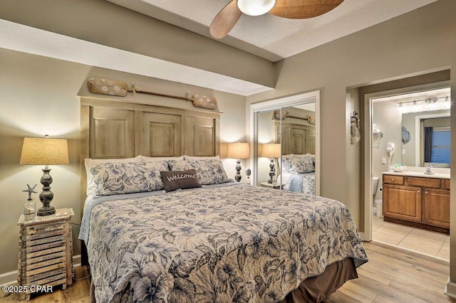 bedroom featuring sink, light hardwood / wood-style flooring, ceiling fan, connected bathroom, and a closet