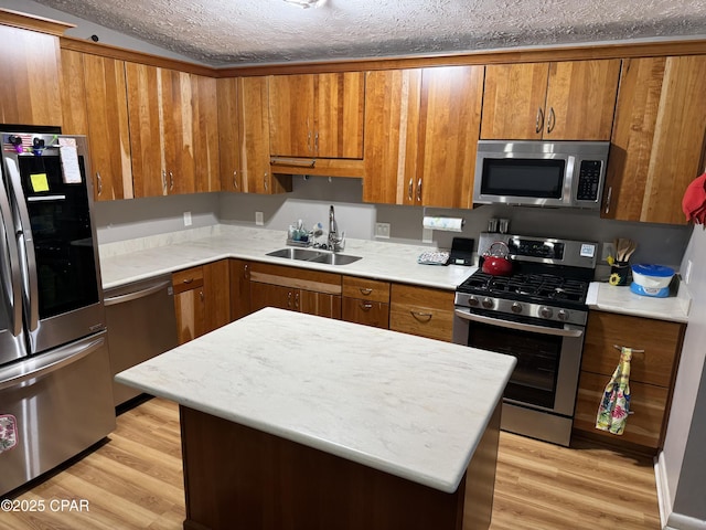 kitchen with light wood-style flooring, appliances with stainless steel finishes, brown cabinets, and a sink