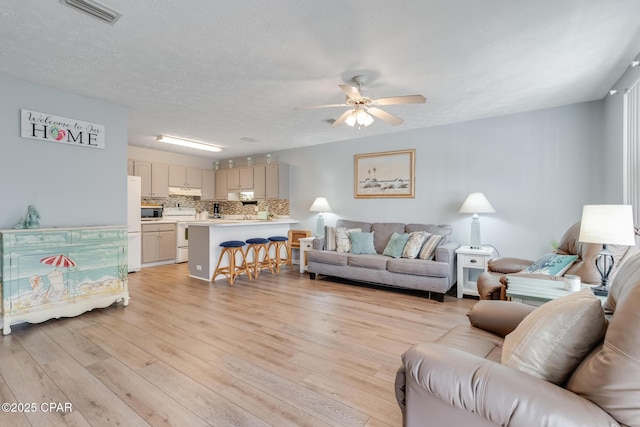 living room featuring a textured ceiling, ceiling fan, and light wood-type flooring