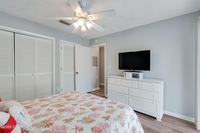 bedroom with two closets, ceiling fan, and light hardwood / wood-style flooring