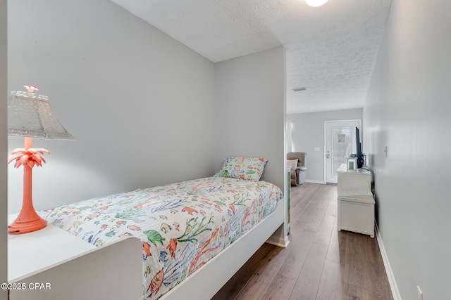 bedroom featuring a textured ceiling and dark hardwood / wood-style flooring