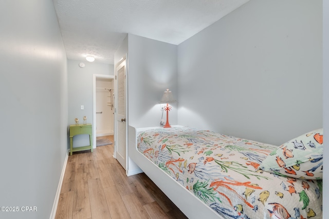 bedroom featuring a textured ceiling, light wood-type flooring, and a closet