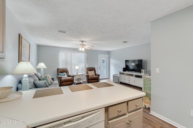 kitchen featuring ceiling fan, dishwasher, a textured ceiling, and light wood-type flooring