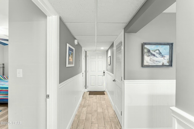 hall with a paneled ceiling and light hardwood / wood-style flooring