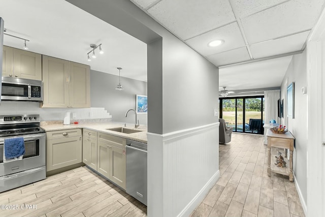 kitchen with sink, appliances with stainless steel finishes, hanging light fixtures, track lighting, and decorative backsplash