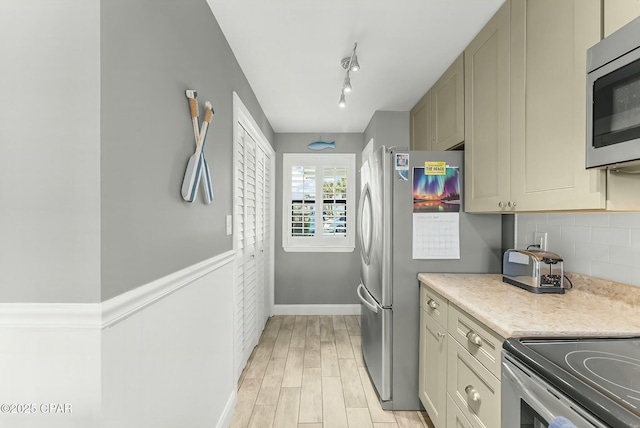 kitchen with decorative backsplash, light hardwood / wood-style flooring, stainless steel appliances, and rail lighting