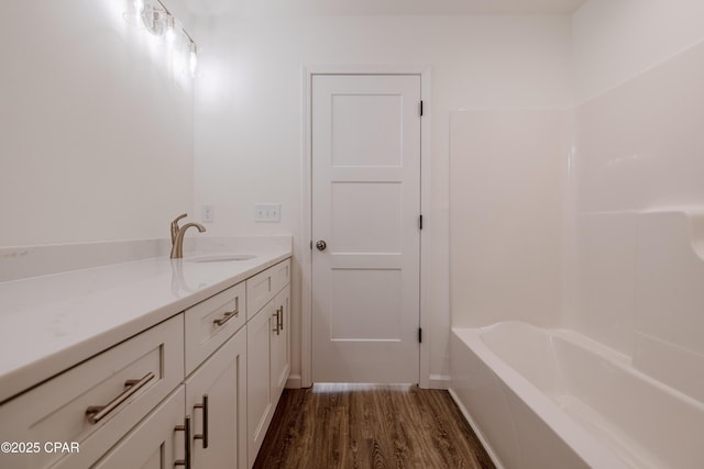 full bath featuring vanity, a bathing tub, and wood finished floors