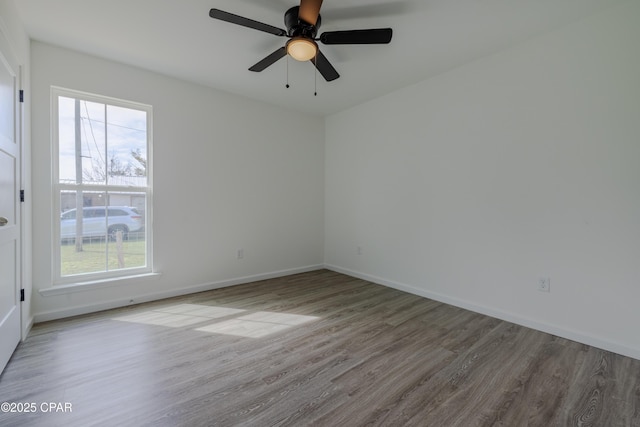 empty room with wood finished floors, a ceiling fan, and baseboards