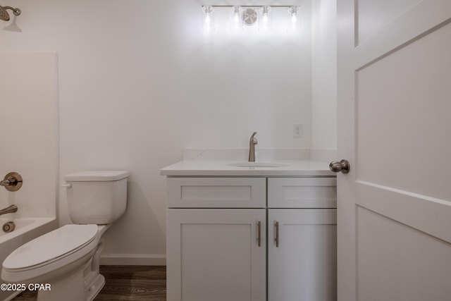 bathroom featuring toilet, wood finished floors, vanity, baseboards, and tub / shower combination