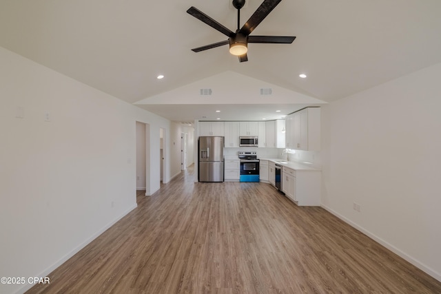 unfurnished living room with visible vents, baseboards, lofted ceiling, light wood-style floors, and a sink