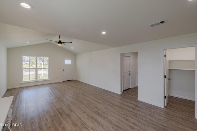 unfurnished living room with visible vents, vaulted ceiling, baseboards, and wood finished floors