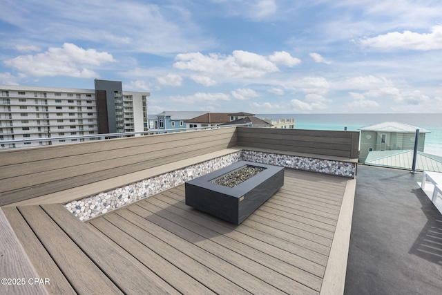 wooden deck with a water view and an outdoor fire pit