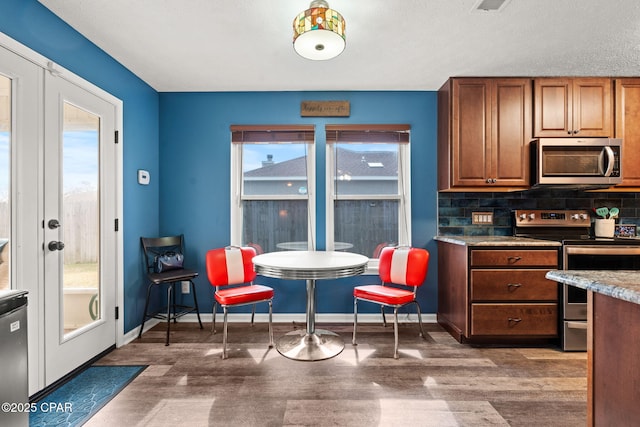 kitchen featuring stainless steel appliances, french doors, backsplash, brown cabinets, and dark wood finished floors