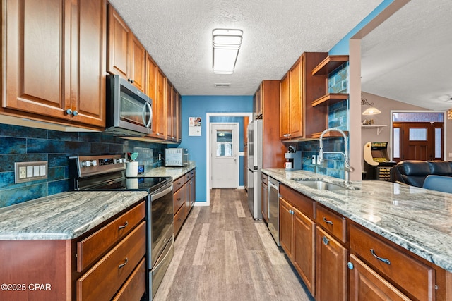 kitchen featuring appliances with stainless steel finishes, brown cabinets, a sink, and open shelves