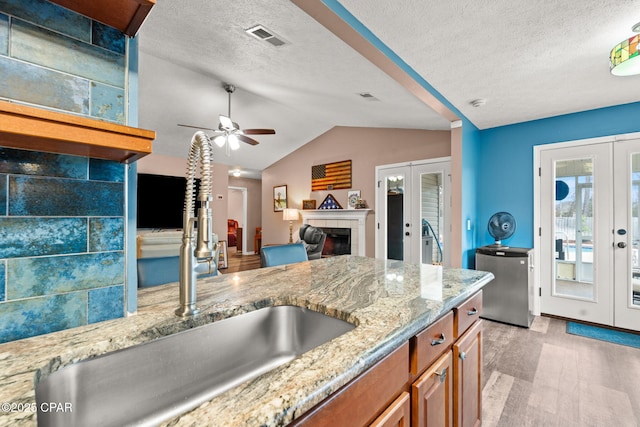 kitchen with brown cabinetry, french doors, a sink, and a tiled fireplace