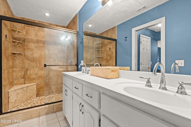 bathroom with a textured ceiling, a sink, visible vents, and tile patterned floors