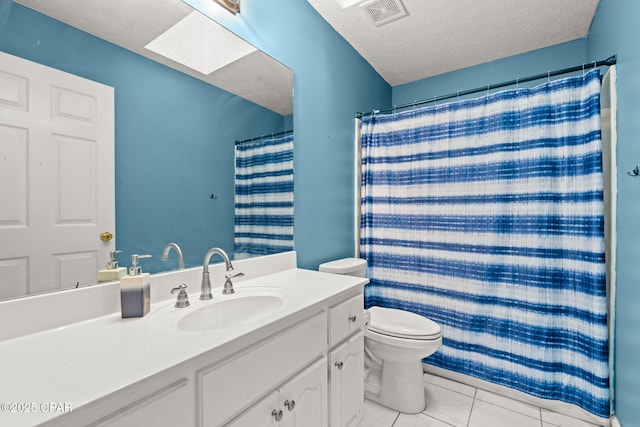 bathroom featuring a skylight, visible vents, toilet, tile patterned flooring, and a textured ceiling