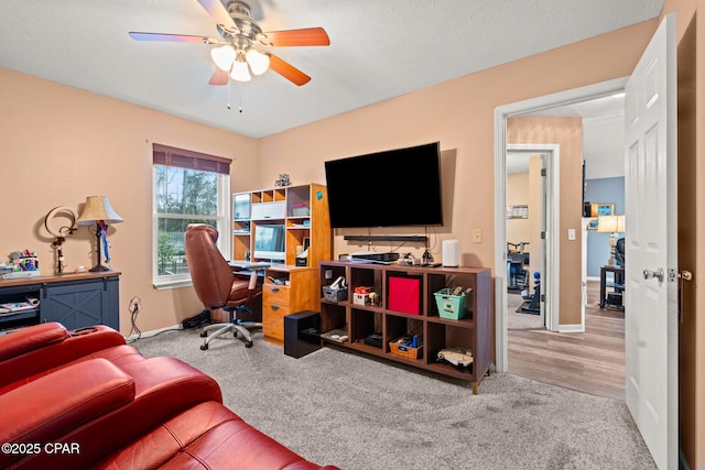 office space with light carpet, a textured ceiling, and a ceiling fan