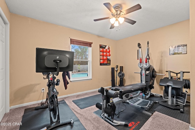 workout room with a ceiling fan, carpet, a textured ceiling, and baseboards