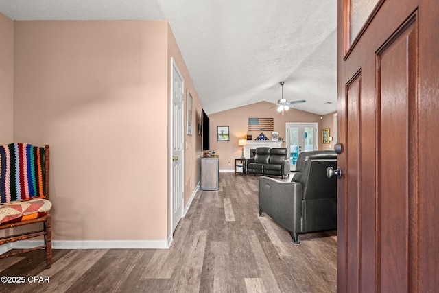 interior space featuring vaulted ceiling, wood finished floors, a ceiling fan, and baseboards