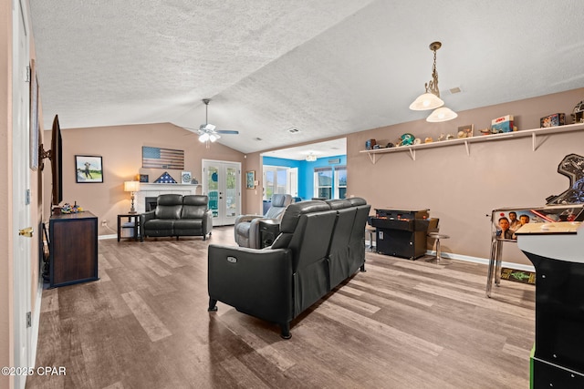 living area featuring lofted ceiling, a textured ceiling, wood finished floors, baseboards, and french doors